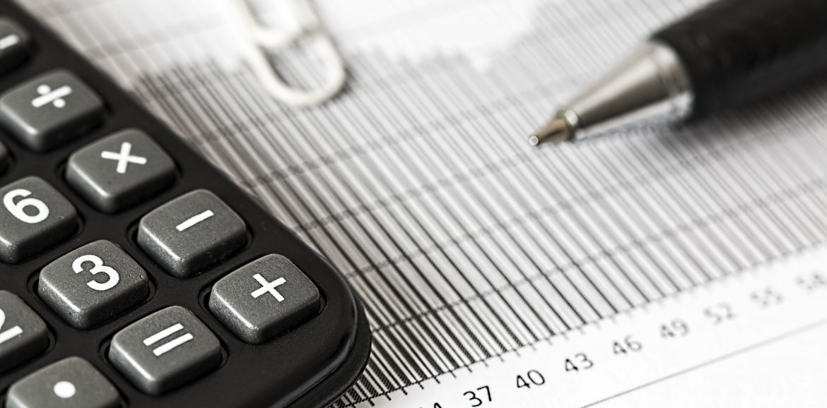 A close up of a calculator, pen and paperclip